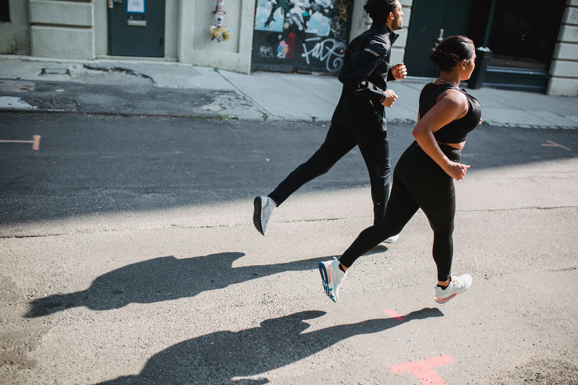 Twee hardlopers lopen in hetzelfde ritme over een zonnige straat